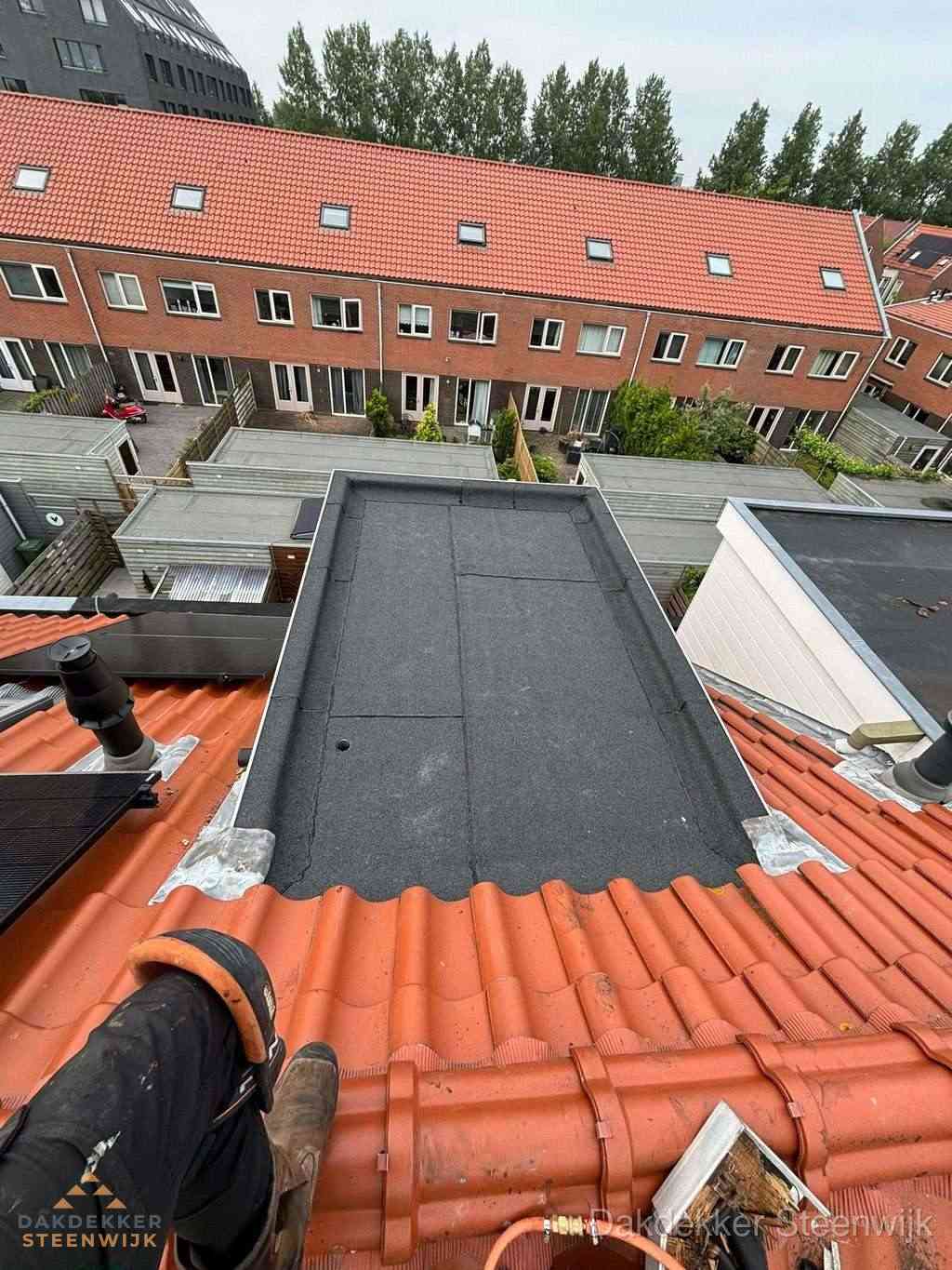 Bitumen dak reparatie op plat dak tussen dakpannen in Steenwijk